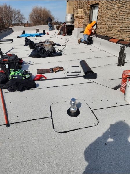 Roofers sealing vents and flashing on a newly installed flat roof