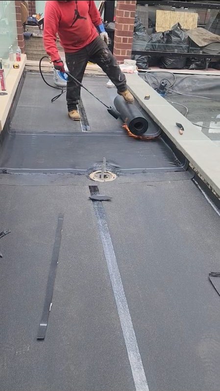 Crew installing a flat roof membrane around a roof drain